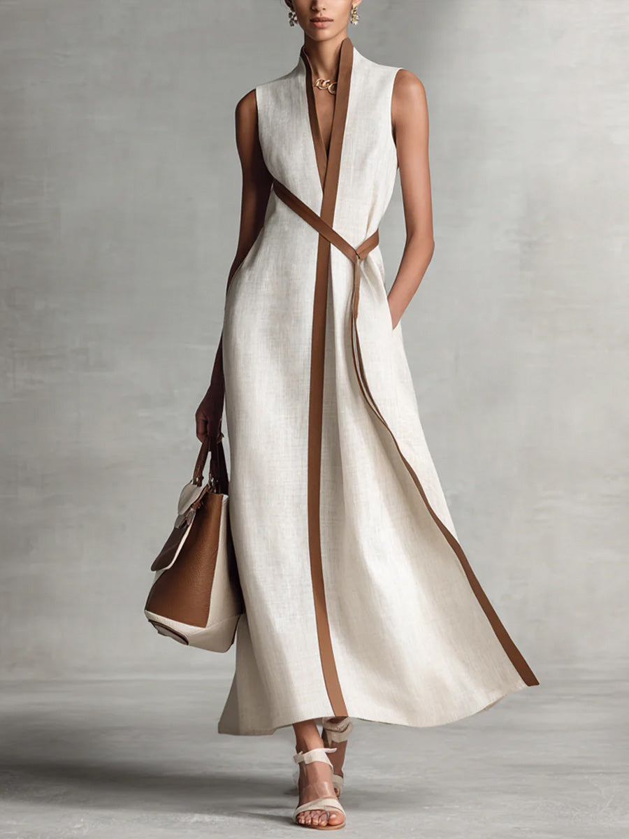 Woman wearing a long white dress with brown accents against a gray background