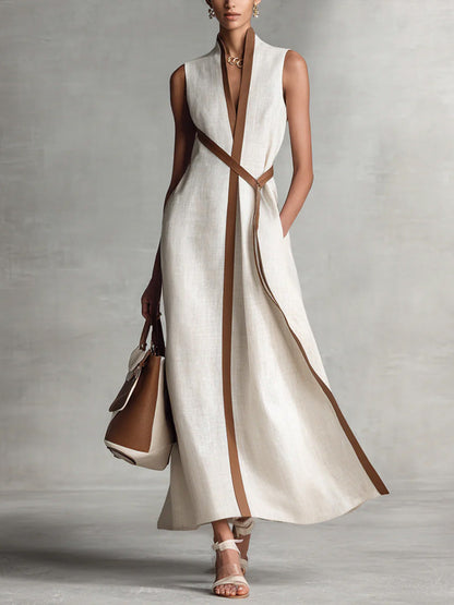 Woman wearing a long white dress with brown accents against a gray background