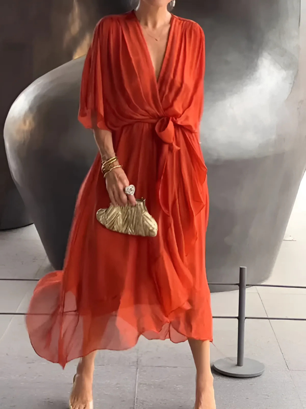 Woman wearing a red dress holding a gold clutch in an indoor setting.