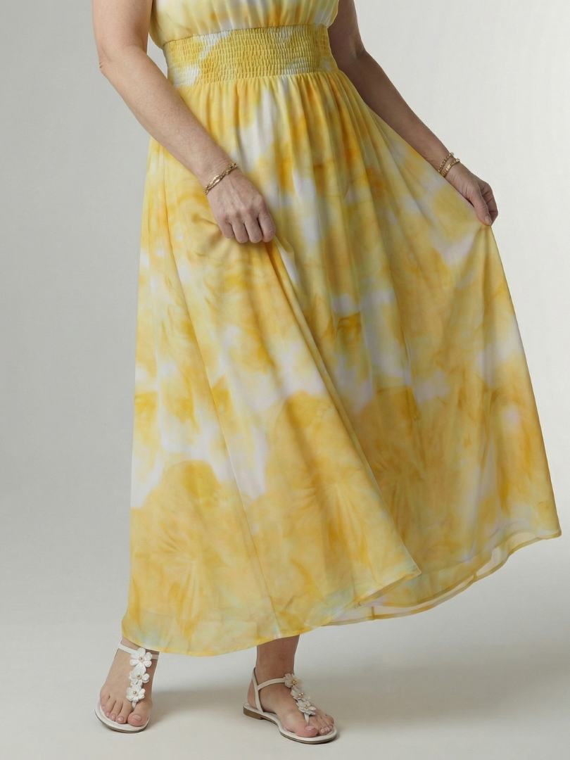 Yellow tie-dye dress worn by a person on a plain background