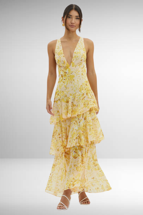 Woman wearing a yellow floral dress on a plain background