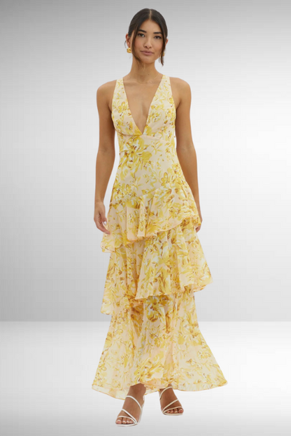 Woman wearing a yellow floral dress on a plain background