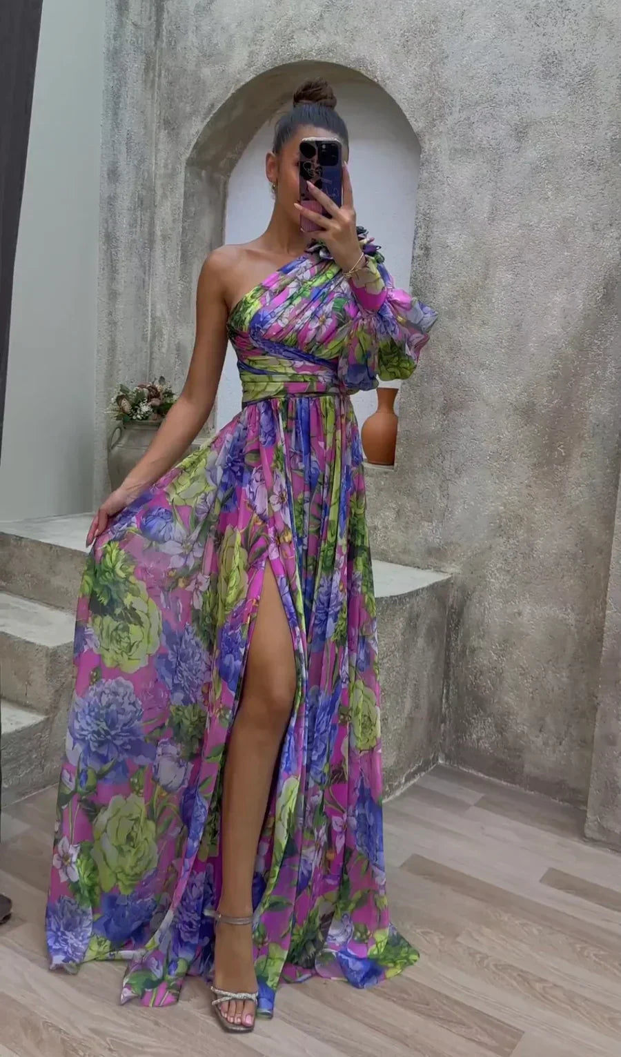 Woman taking a mirror selfie wearing a colorful floral dress in an indoor setting.