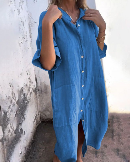 Woman wearing a blue dress against a white wall.
