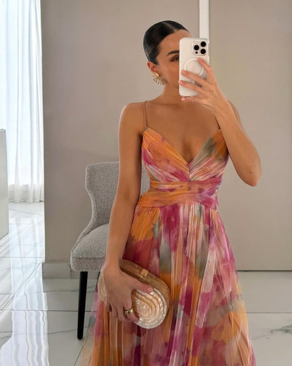 Woman taking a mirror selfie wearing a colorful dress in a room with a chair and window.