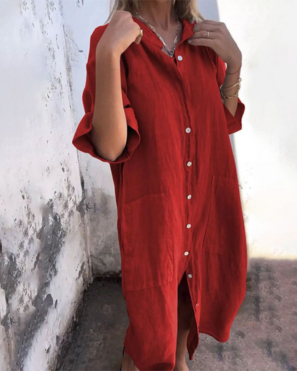 Person wearing a red dress with white buttons against a textured wall.