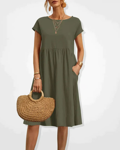 Woman wearing an olive green dress holding a woven bag on a white background
