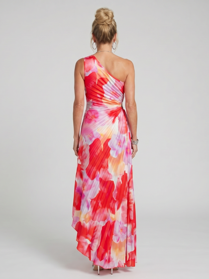 Woman wearing a colorful one-shoulder dress on a plain background