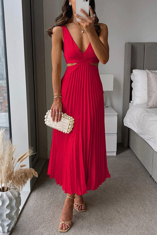 Woman in a red dress taking a mirror selfie in a bedroom.