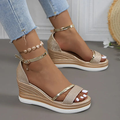 Gold wedge sandals worn with light blue jeans on a neutral background