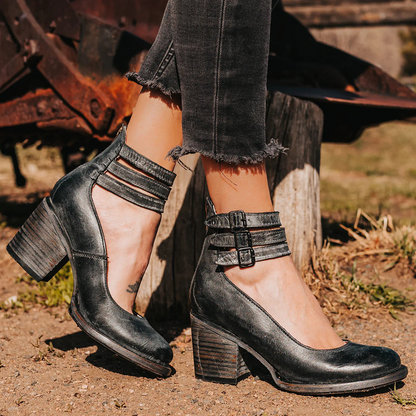 Black heeled shoes worn with ripped jeans against a rustic background