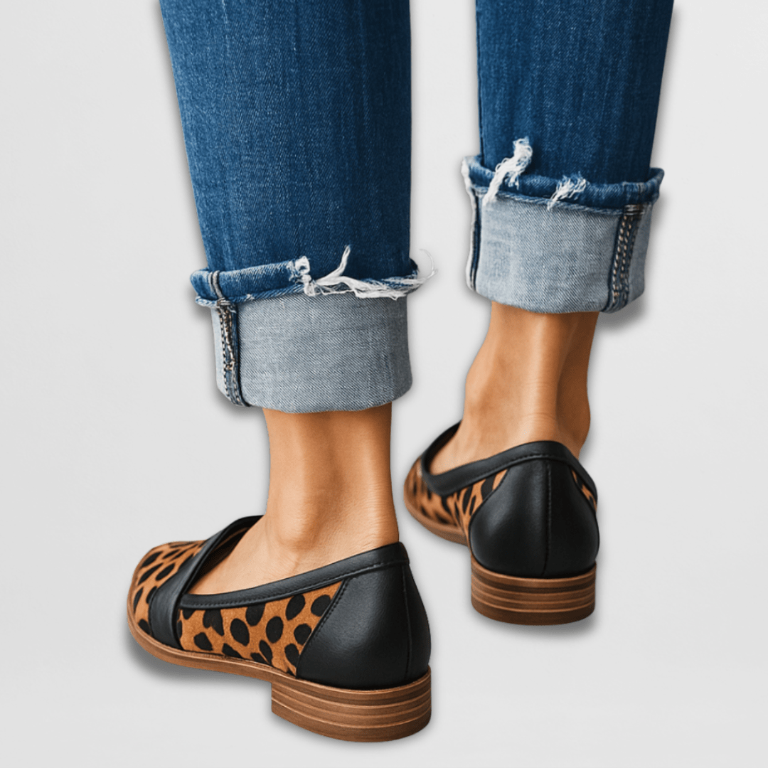 Leopard print flats worn with rolled-up jeans on a light gray background