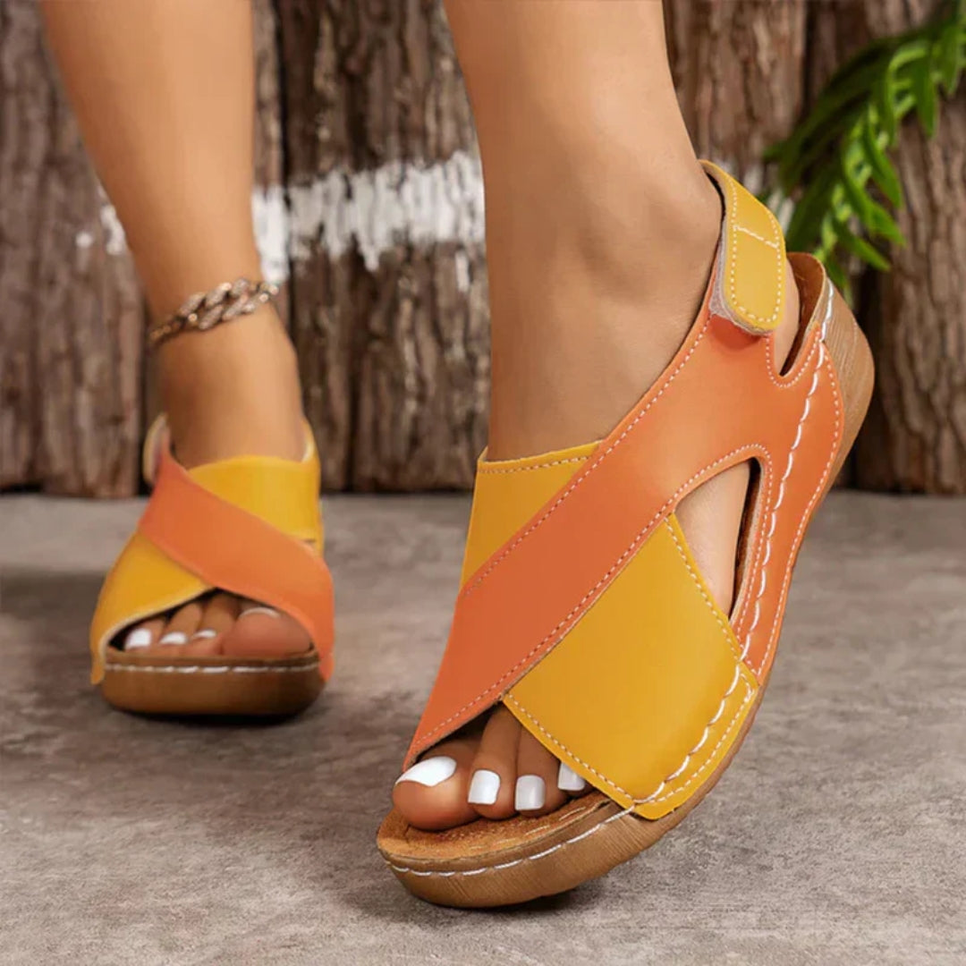 Orange and yellow sandals worn by a person on a neutral background
