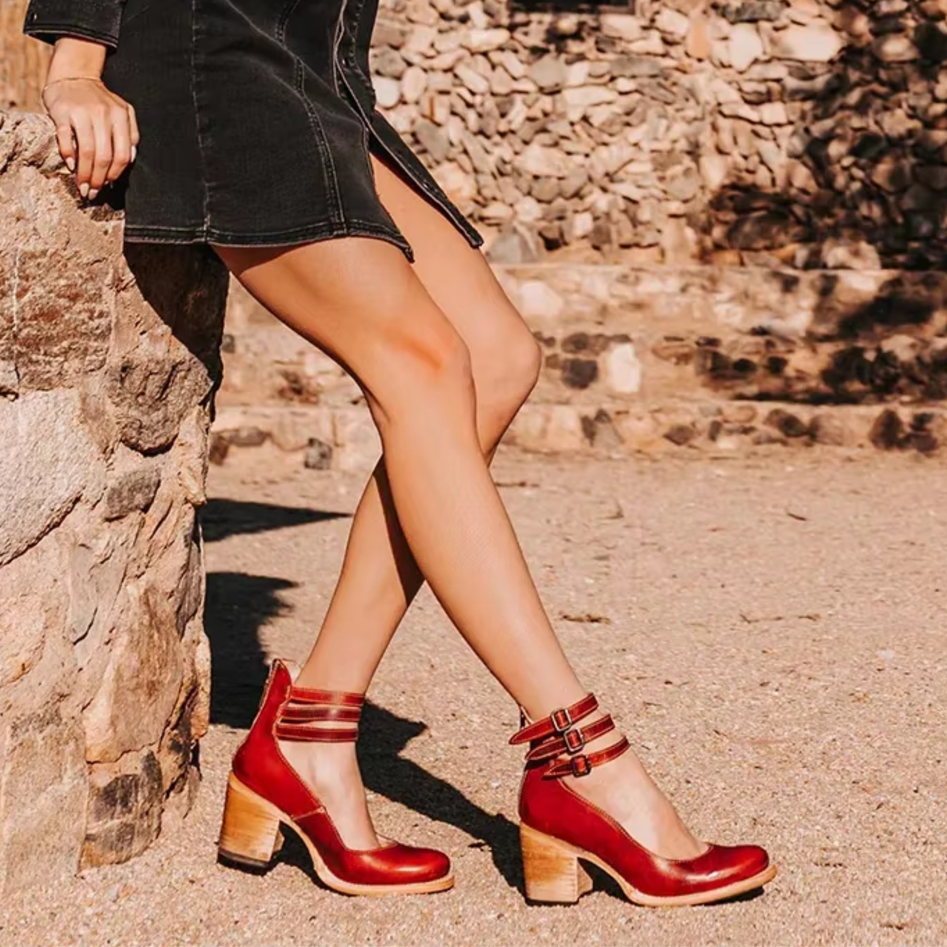 Person wearing red shoes with wooden soles against a stone wall background