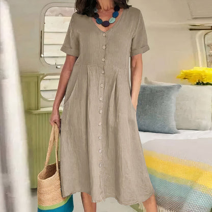 Woman wearing a beige dress holding a straw bag in an indoor setting with colorful decor.