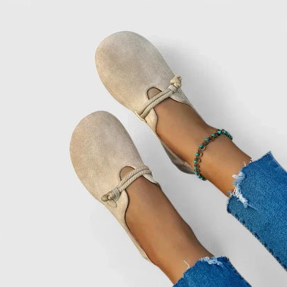Beige loafers worn with blue jeans on a white background
