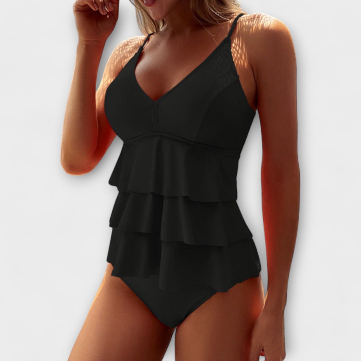 Black ruffled swimsuit worn by a model on a white background