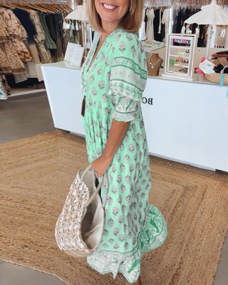 Woman in a light green dress with floral pattern holding a white handbag in a store setting.