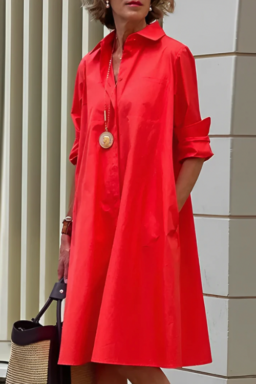 Person wearing a red dress standing against a light-colored wall.