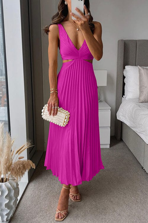 Woman in a bright pink dress taking a mirror selfie in a bedroom.