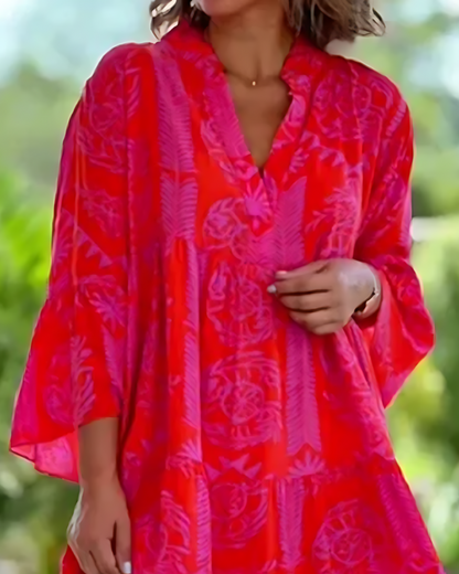 Person wearing a bright red and pink patterned dress with a blurred green background