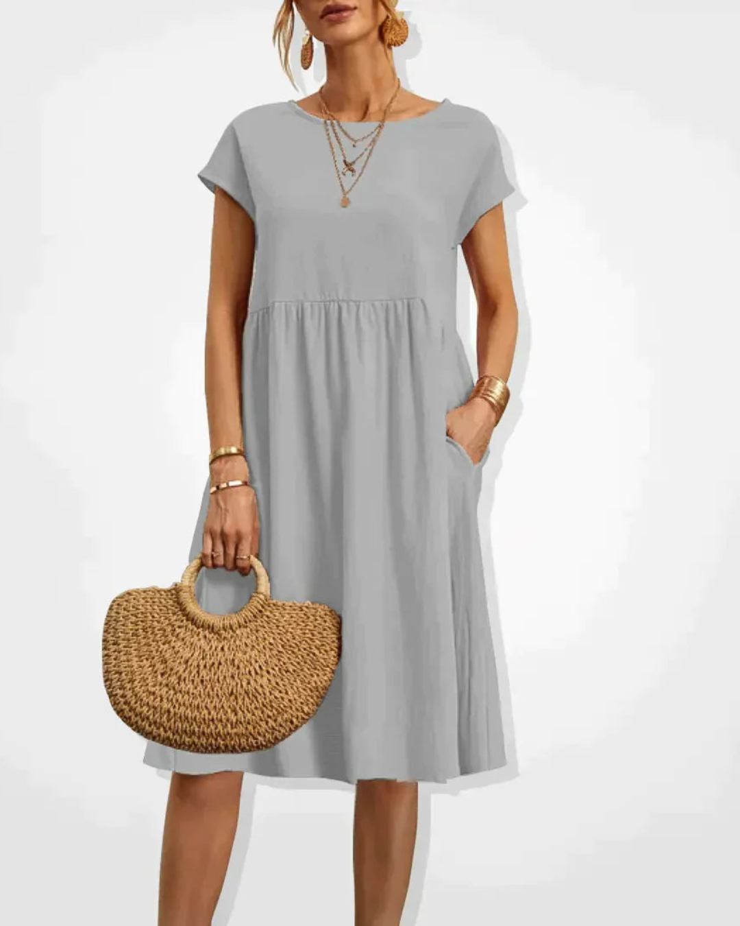 Woman wearing a gray dress holding a woven handbag on a white background