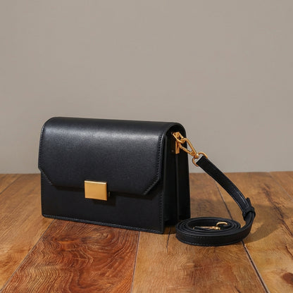 Black crossbody bag with gold accents on a wooden surface