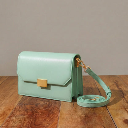 Mint green leather purse with gold accents on a wooden surface