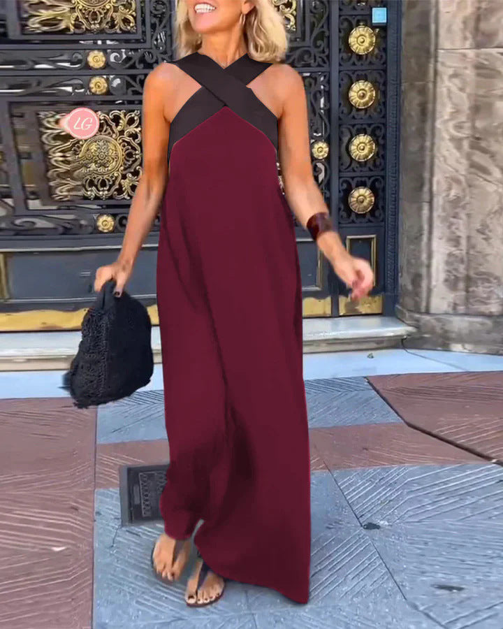 Woman in a burgundy dress with black straps standing in front of an ornate door.