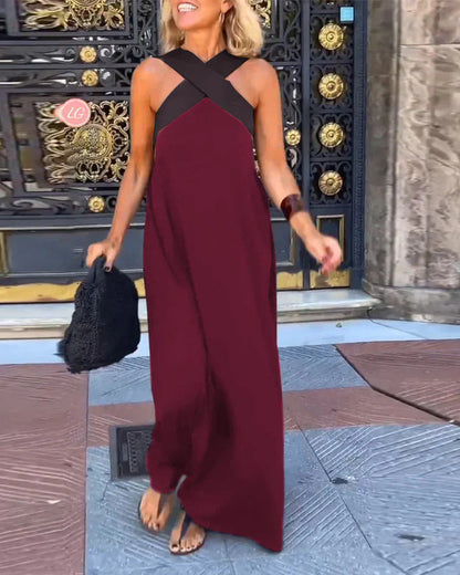 Woman in a burgundy dress with black straps standing in front of an ornate door.