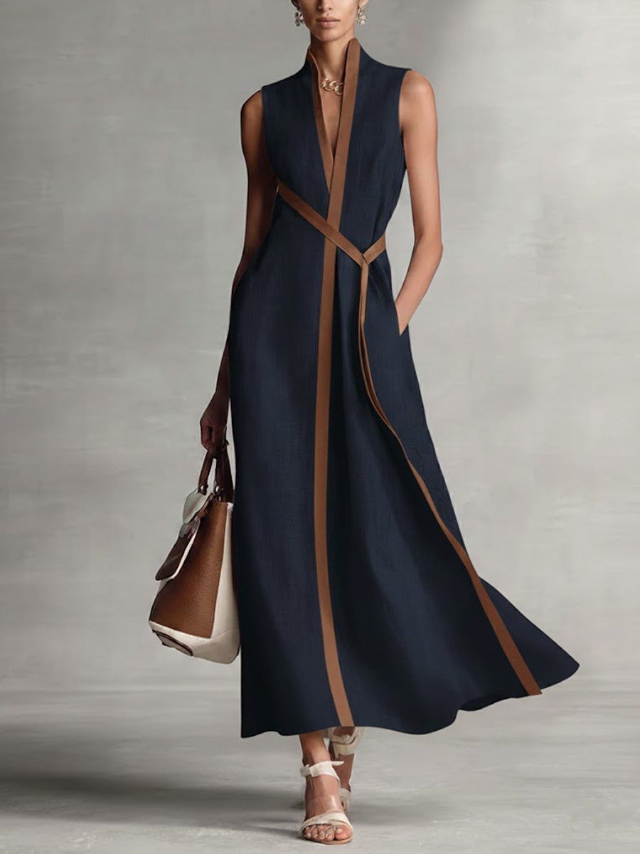 Woman wearing a navy dress with brown accents against a gray background