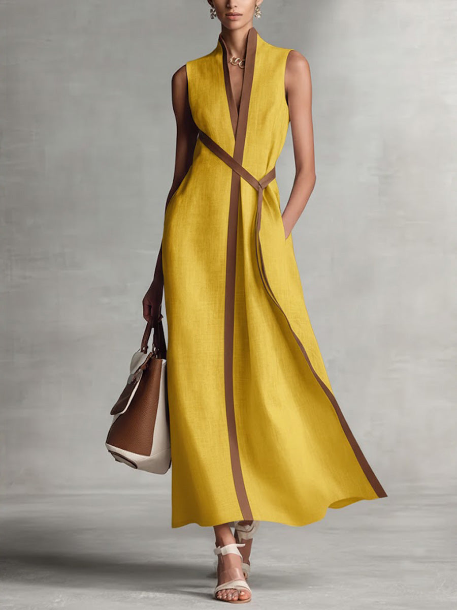 Woman wearing a yellow dress with brown accents against a gray background