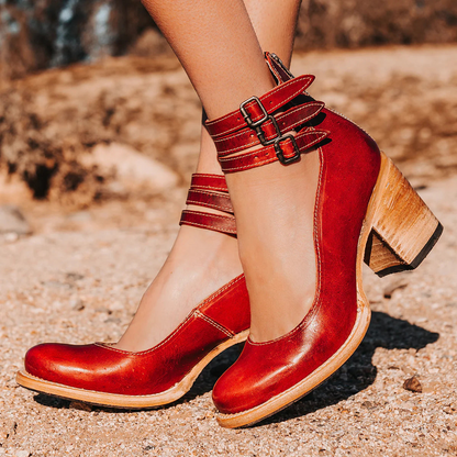 Red high-heeled shoes with wooden soles on a blurred natural background