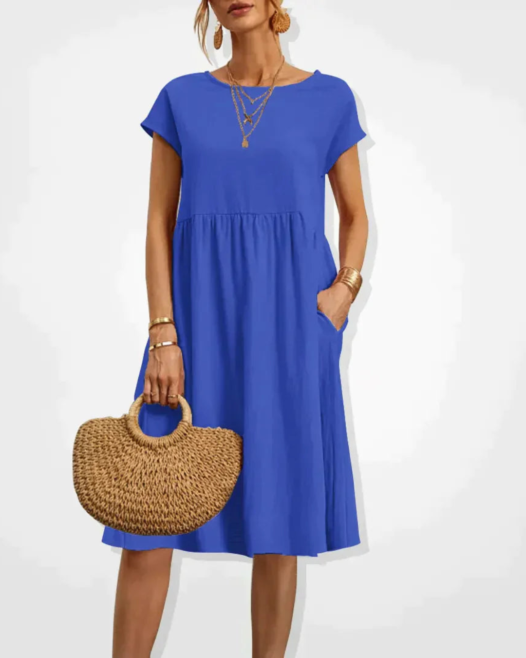 Woman wearing a blue dress holding a woven bag on a white background