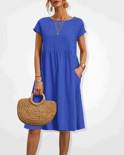 Woman wearing a blue dress holding a woven bag on a white background
