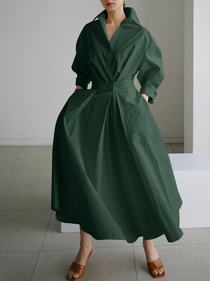 Person wearing a green dress standing against a neutral background