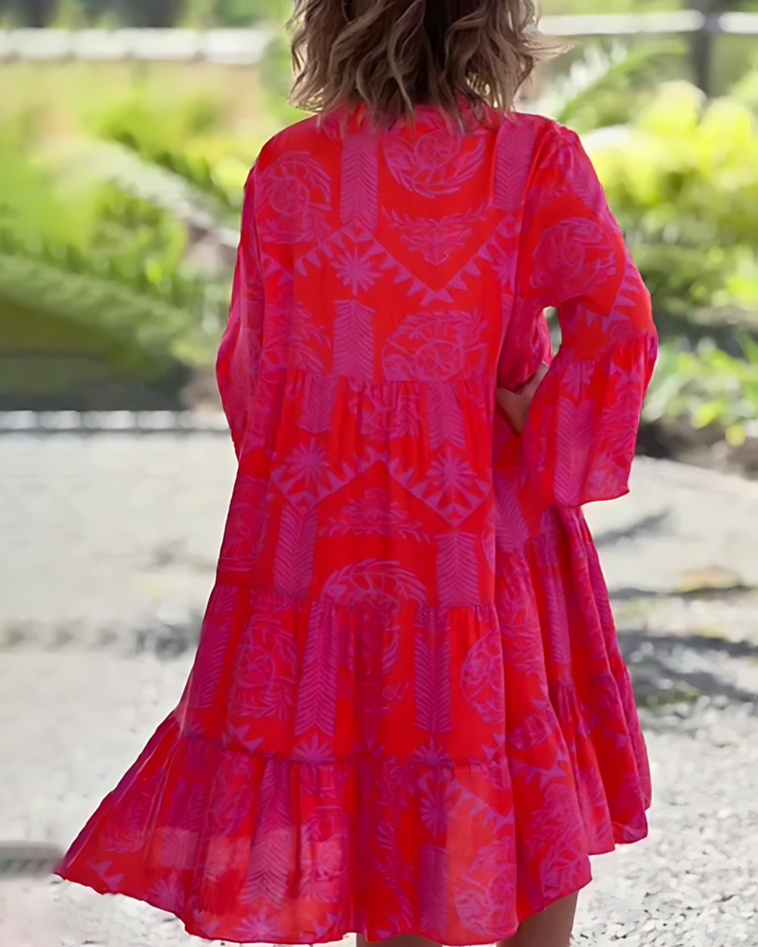 Red patterned dress worn by a person with a blurred natural background
