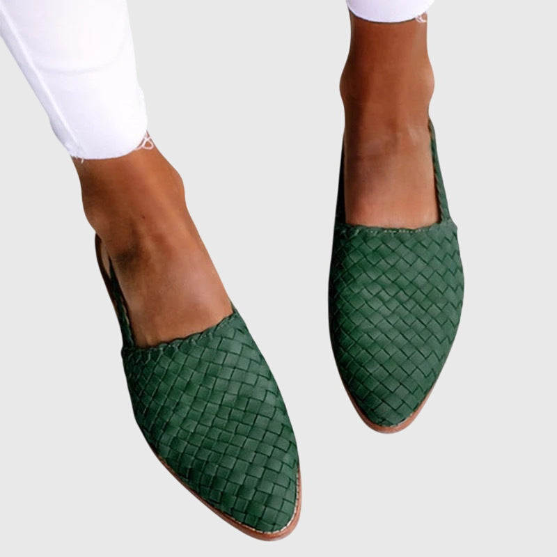 Green woven shoes worn with a white outfit on a light gray background