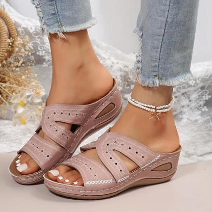 Pink sandals worn with light blue jeans on a neutral background