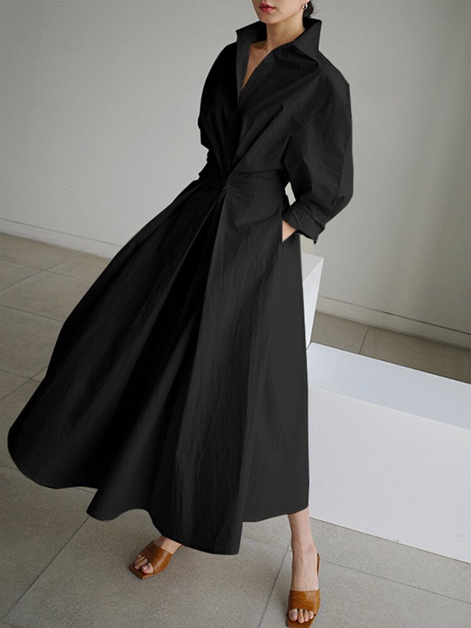 Person wearing a long black coat in a minimal indoor setting