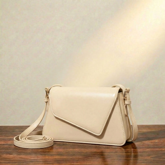 Beige leather shoulder bag on a wooden surface with a neutral background