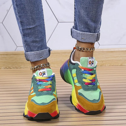 Colorful sneakers with rainbow laces worn with rolled-up jeans on a wooden floor.
