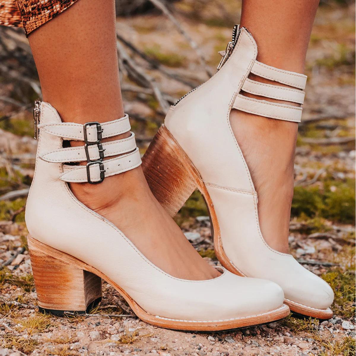 White high-heeled shoes with wooden soles worn outdoors on a natural background
