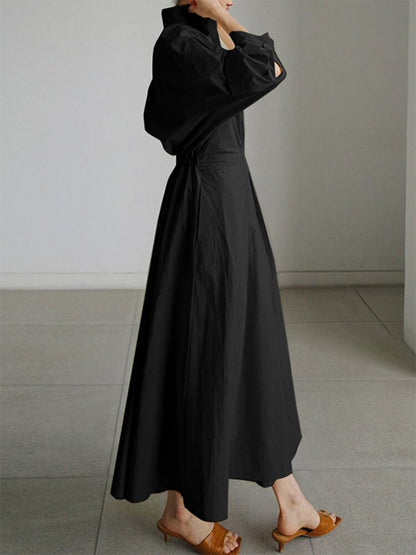 Person wearing a black outfit with a high collar in a minimalistic setting