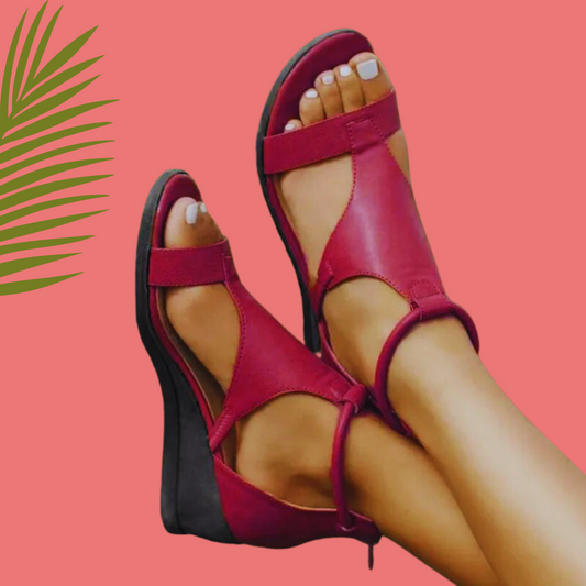 Red wedge sandals worn with a pink background