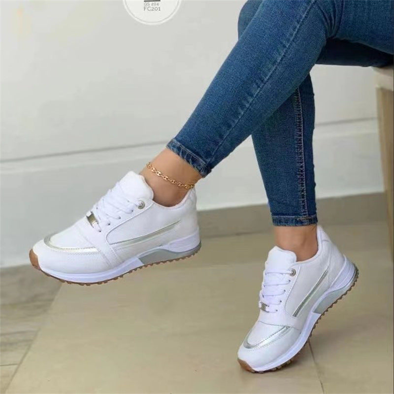 White sneakers worn with blue jeans on a light background
