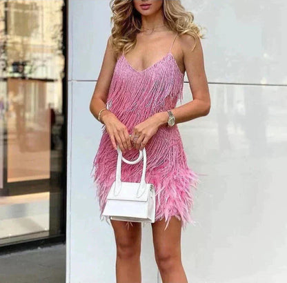 Woman wearing a pink fringe dress holding a white handbag against a light background