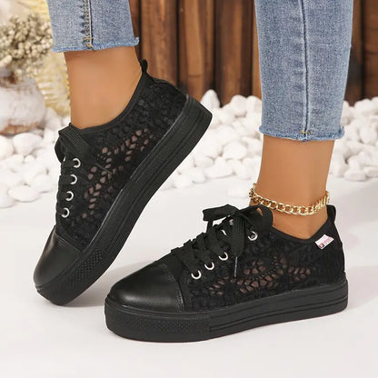 Black lace-up sneakers worn with denim jeans on a light background