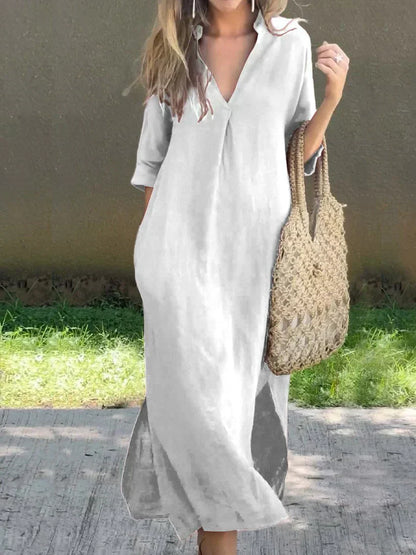 Woman wearing a light gray dress holding a woven bag outdoors.