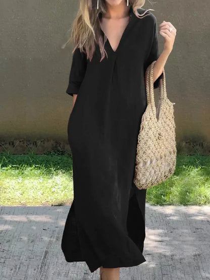 Person wearing a black dress holding a woven bag outdoors.